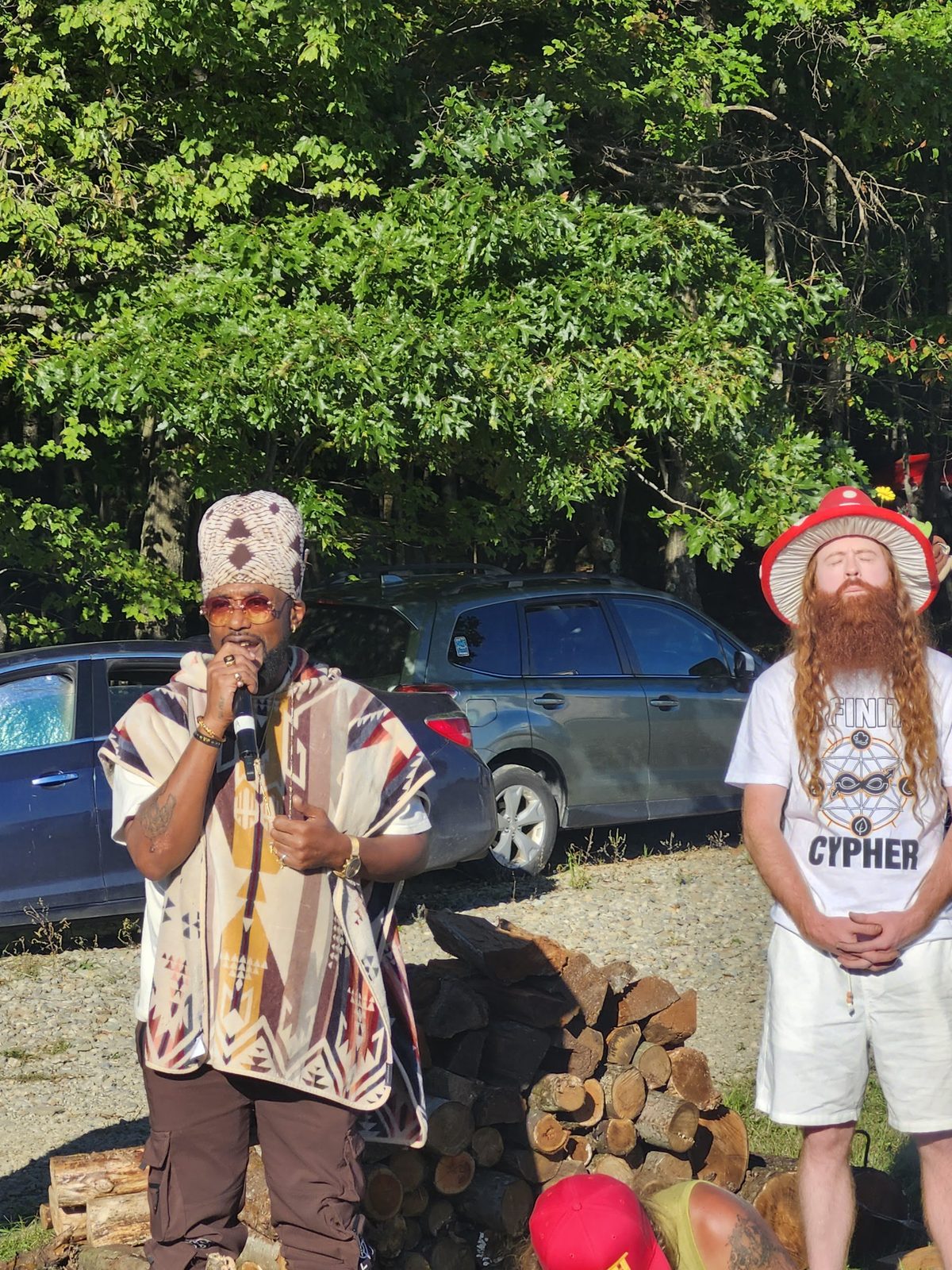 Two artists by the woodpile, one on the mic