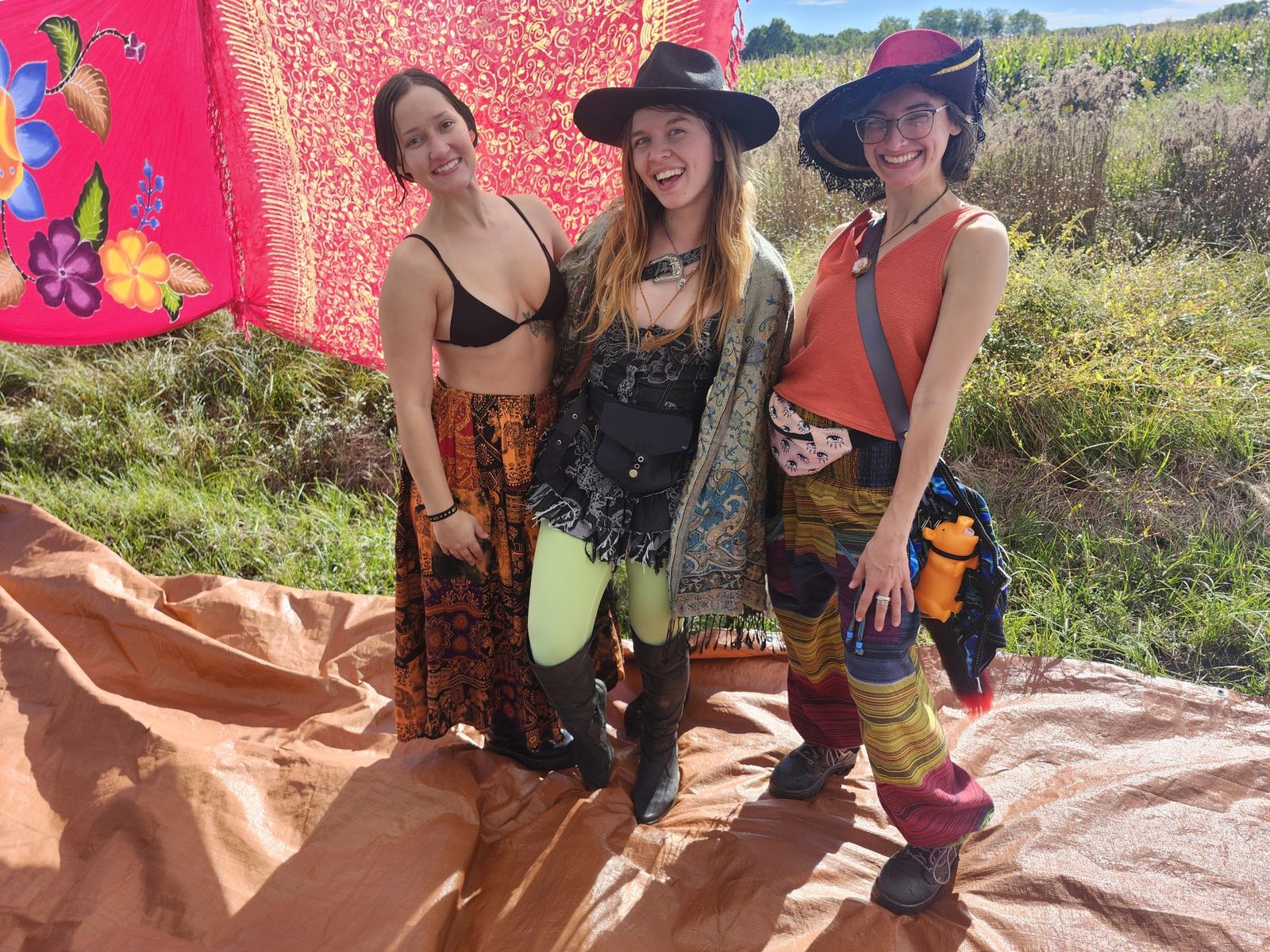 Three friends posing in front of a pink hanging backdrop