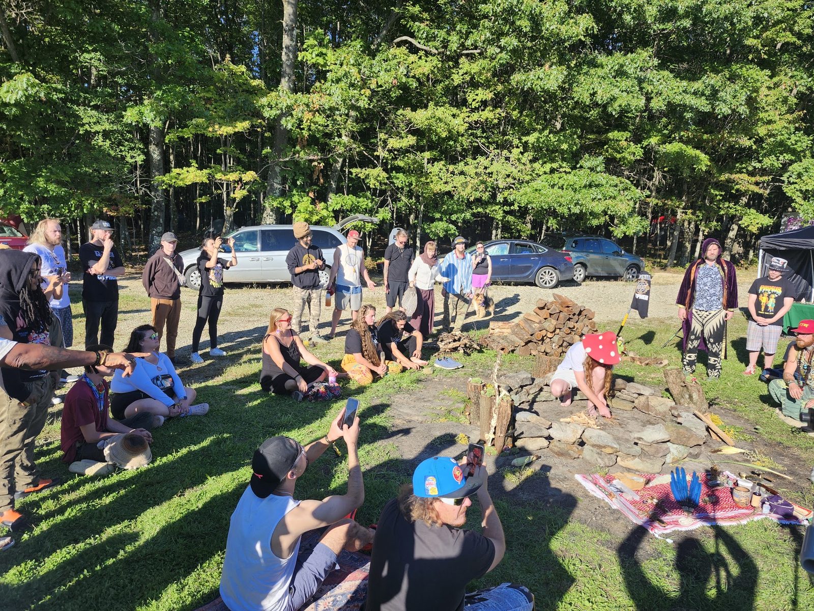 A wide circle of people around the stone mandala in the woods